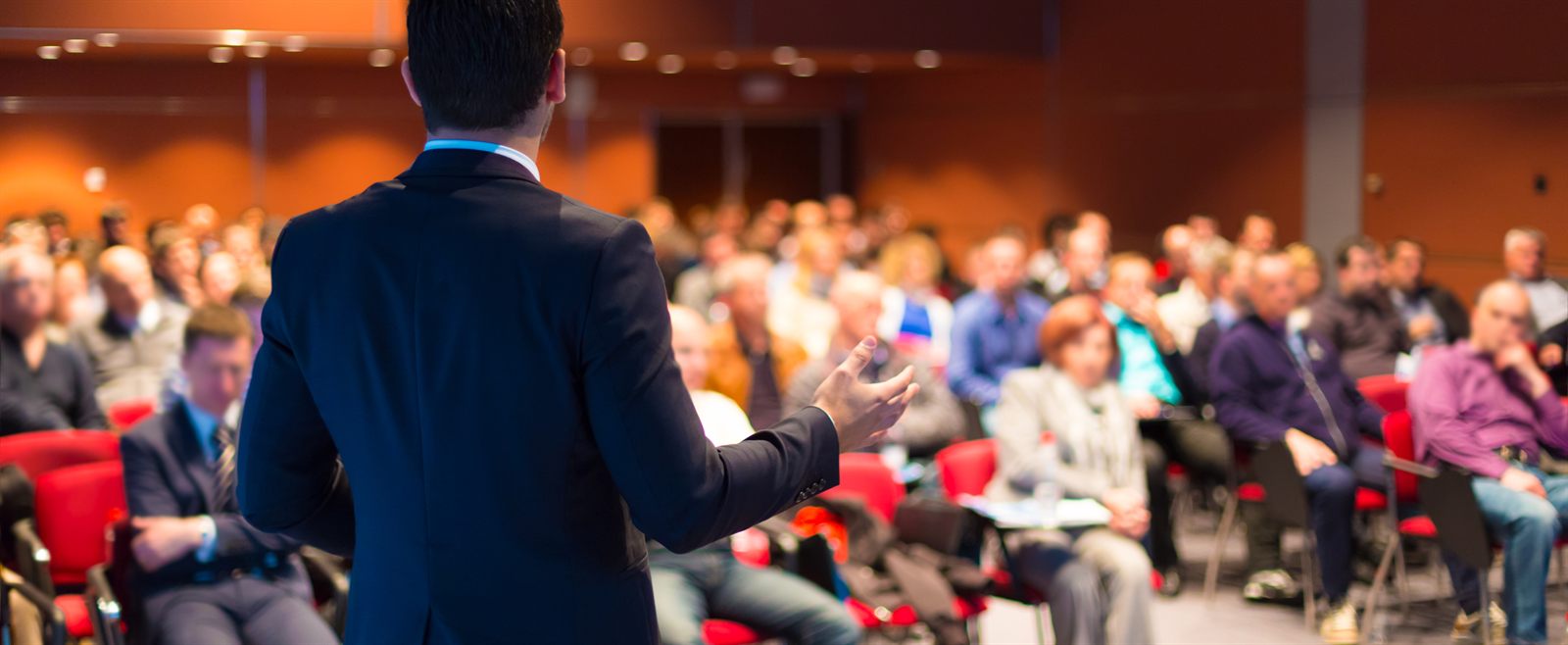 Speaker addressing a large seated audience at a conference session
